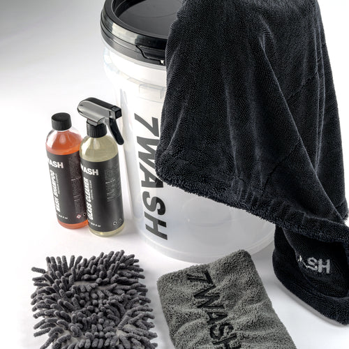 7WASH Starter Wash kit featuring a transparent wash bucket with black branding, one 500ml bottle of premium auto wash shampoo, a grey microfiber wash mitt, a grey drying towel, and a large black microfiber cloth.